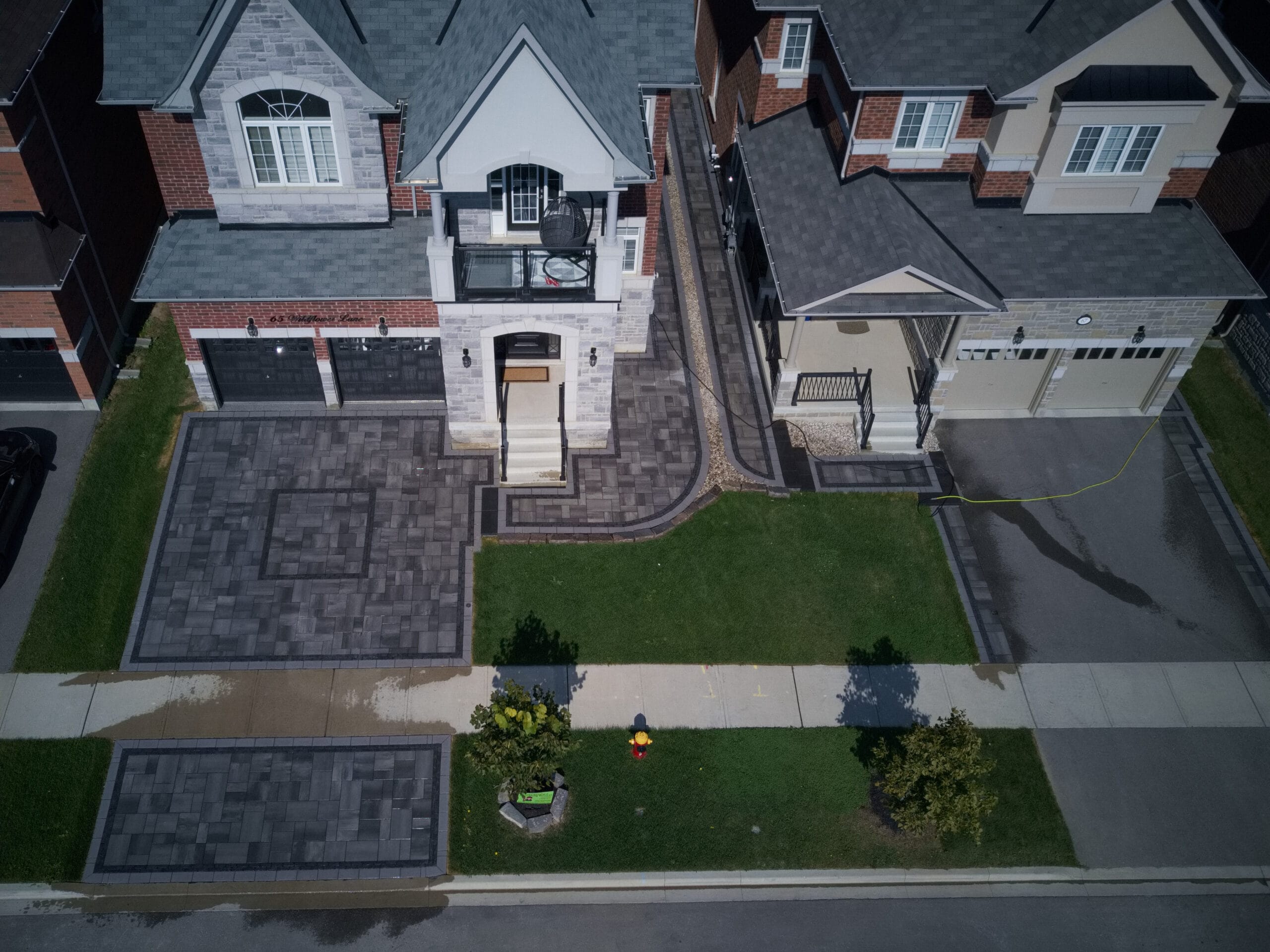 aerial view of a house with an interlock paver driveway and curving walkways